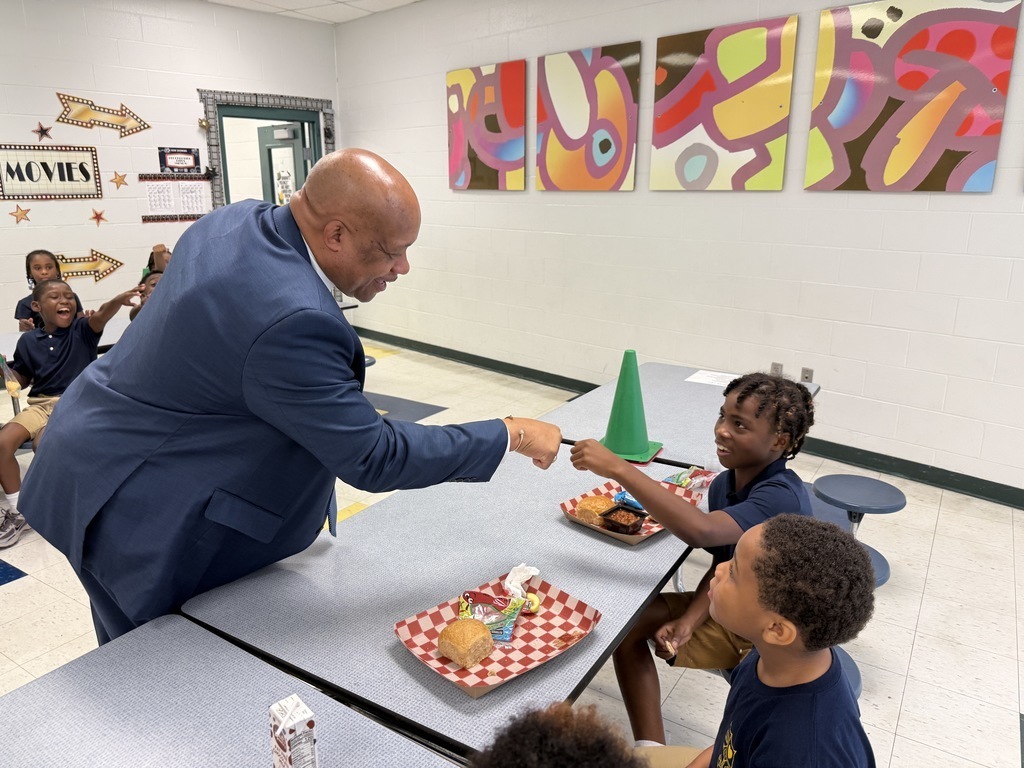 Dr. Yearwood does a fist bump with a student at a lunch table. 