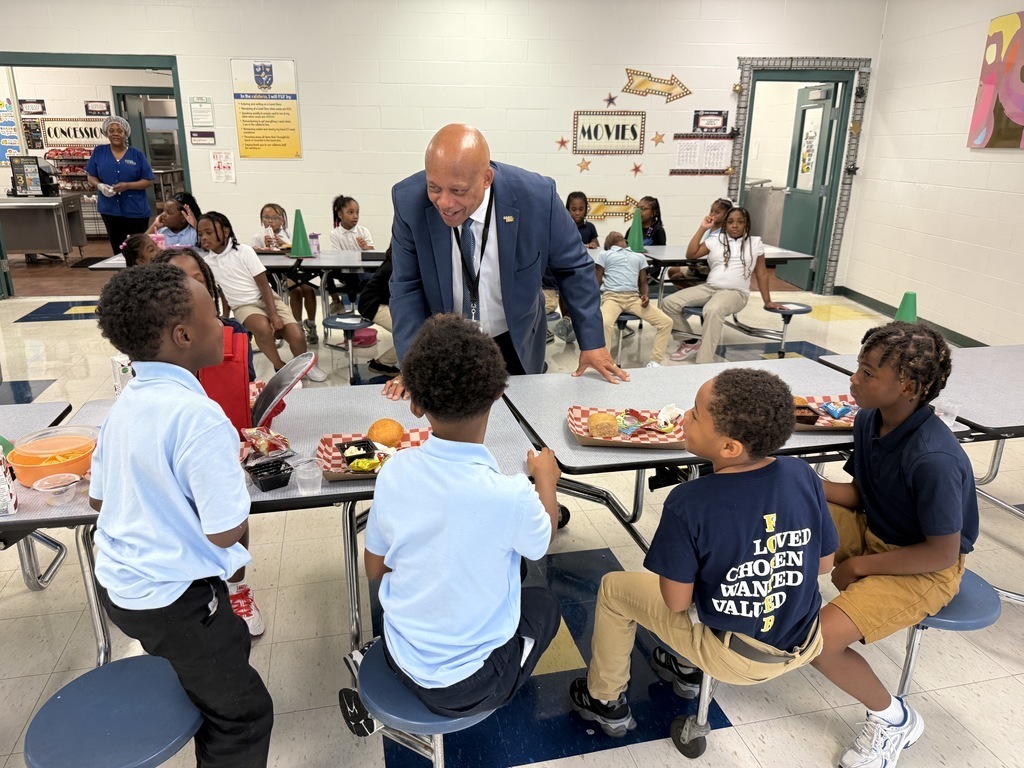 Dr. Yearwood talks to students sitting at a lunch table.
