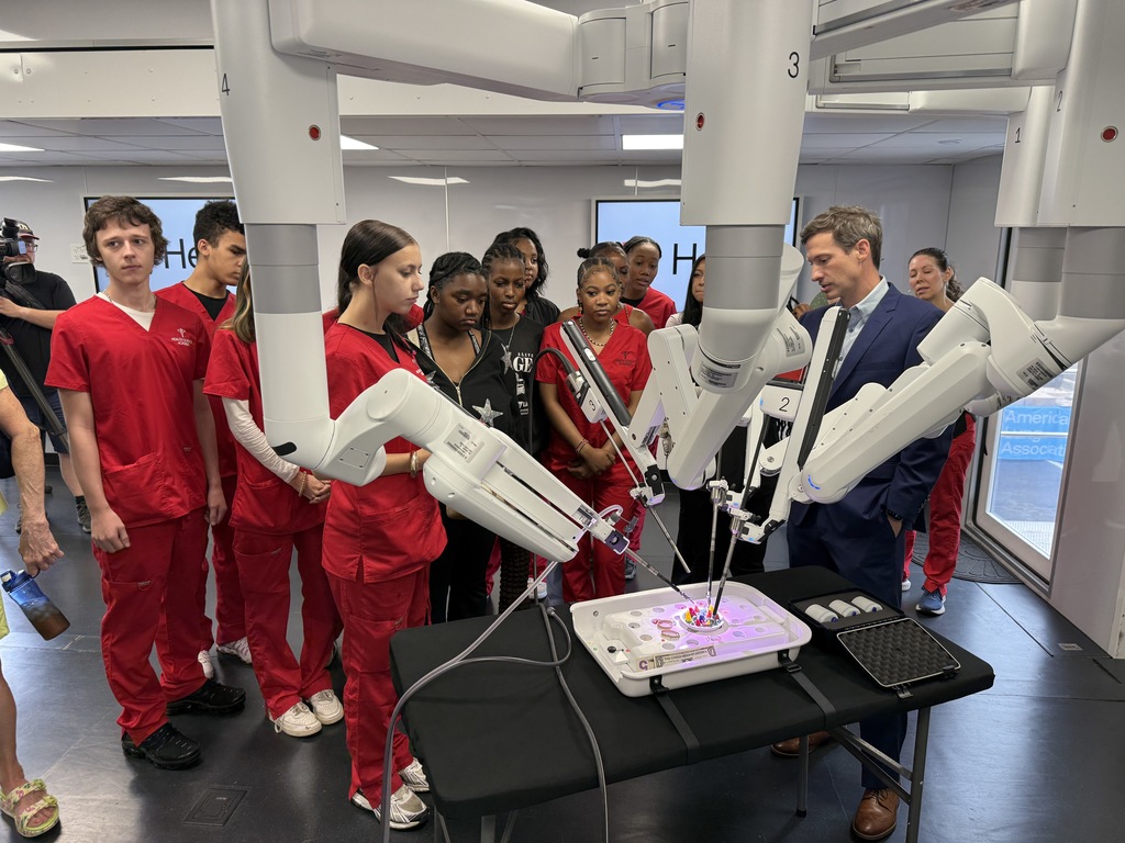 Students and an adult stand near medical machinery.