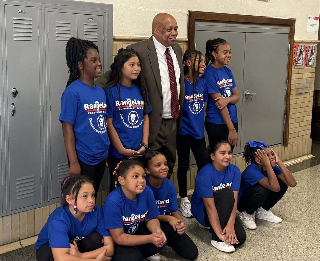 Dr. Yearwood poses for a picture with nine JCPS students in a school hallway. 