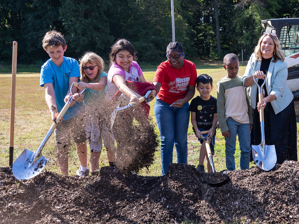 Six students and an adult use shovels to scoop dirt during a groundbreaking ceremony at Kerrick Elementary School. 