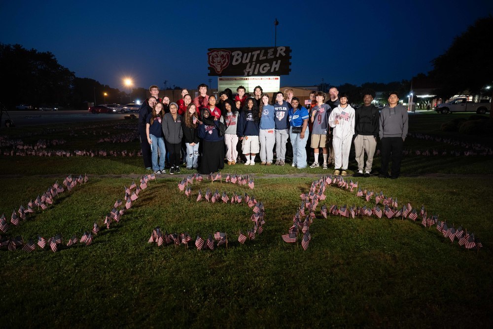Butler Traditional High School students stand behind American flags placed in the ground to spell out "USA"