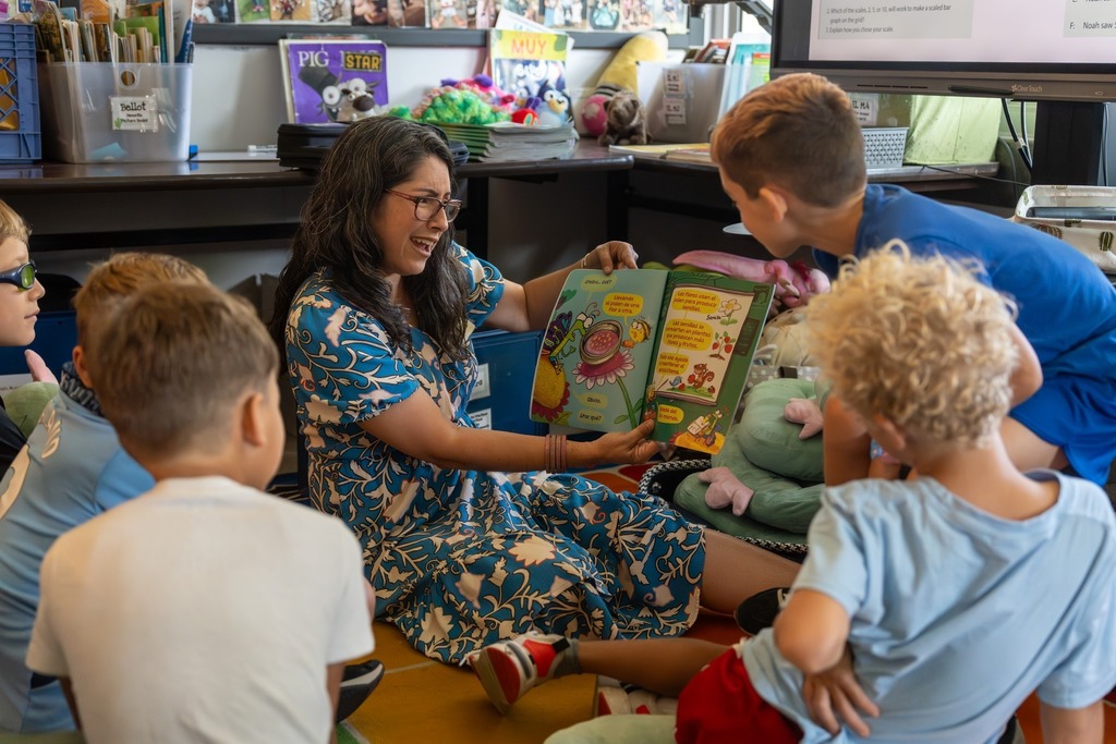 An adult reads to students.
