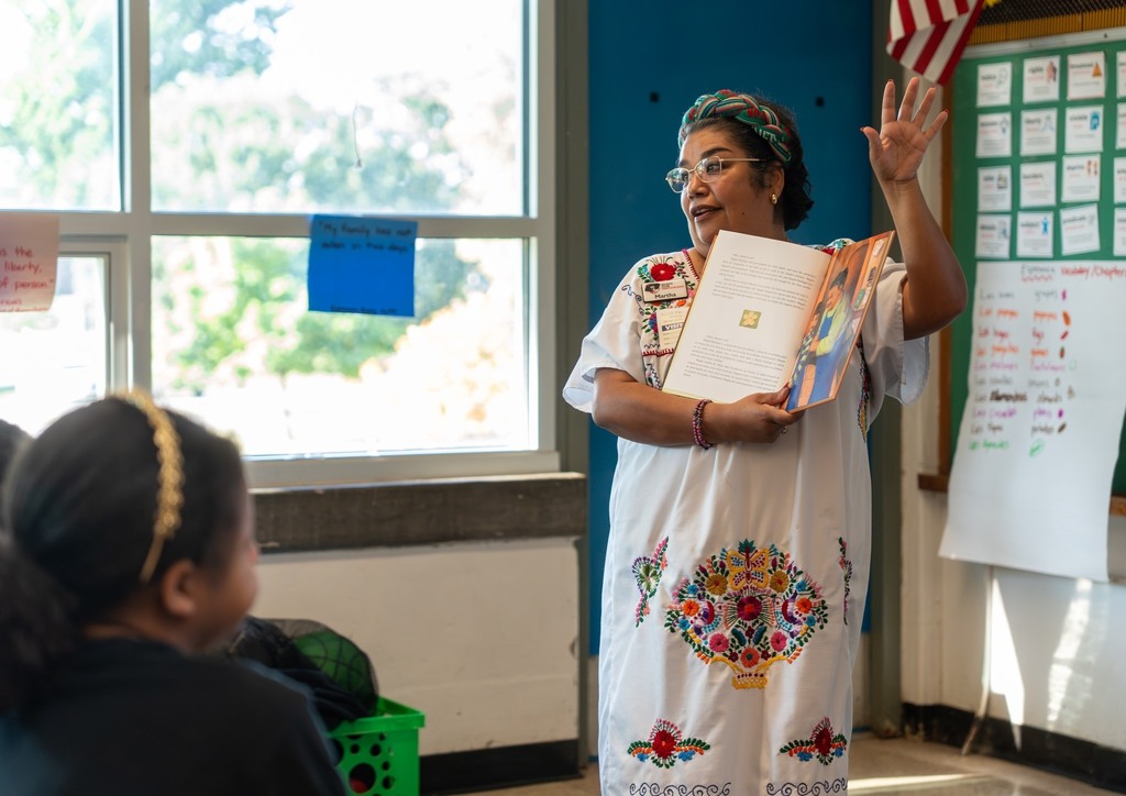 An adult reads to students.