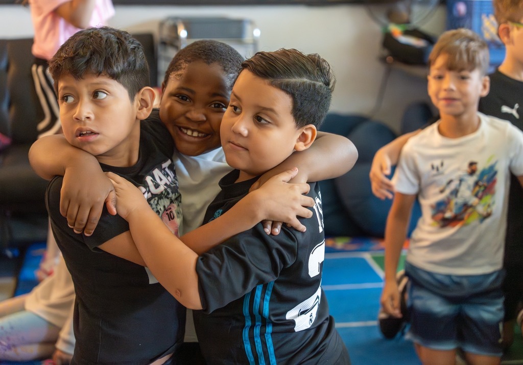 Three students hug each other.