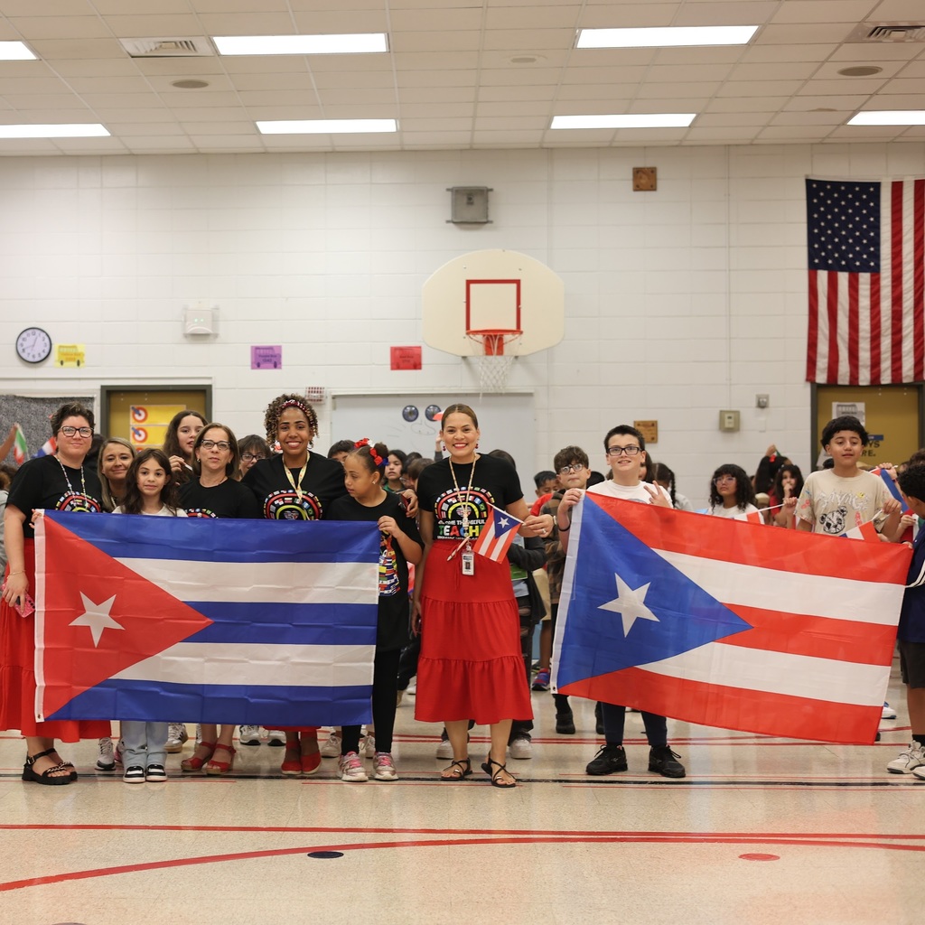 Students and adults hold flags during a Hispanic Heritage event.