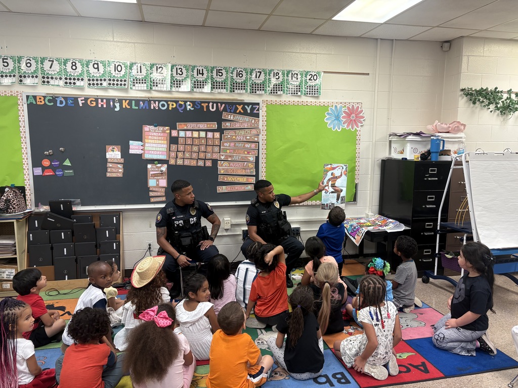 Police officers read to students in a classroom. 