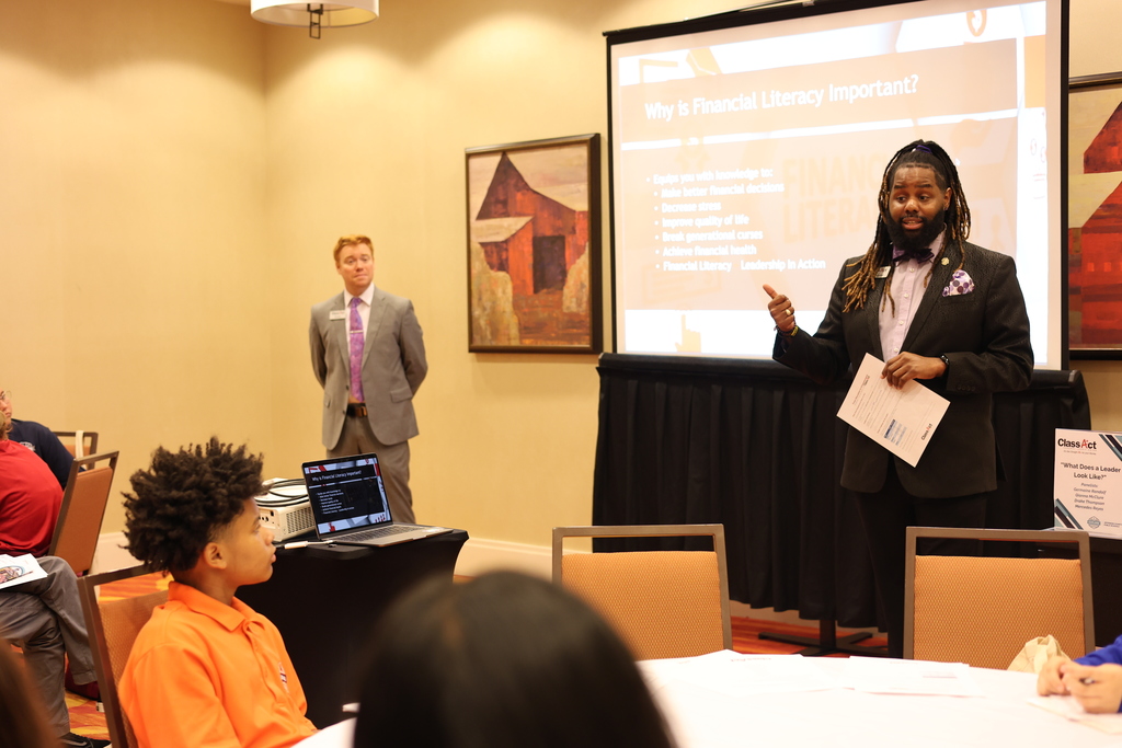 Two adults present to a room of students.