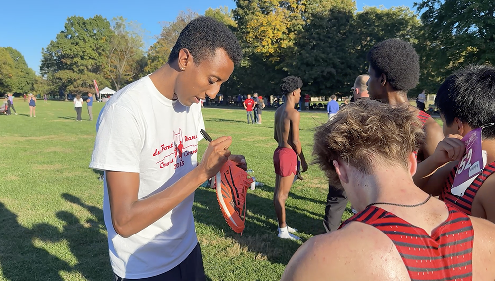 Yared Nuguse signs a shoe for a student.