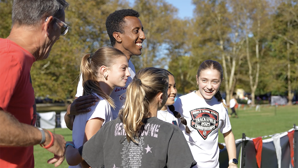 Yared Nuguse poses for a picture with students.
