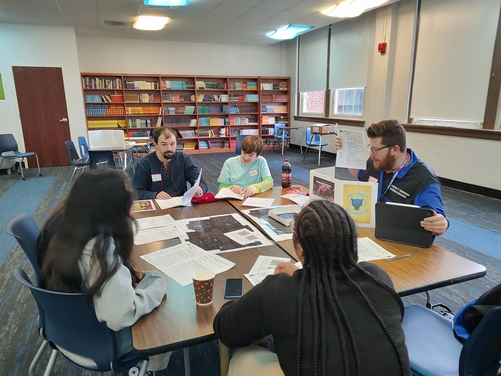 Mr. Vincent as the Dragon Master explaining how to play Dungeons and Dragons to some students and a parent