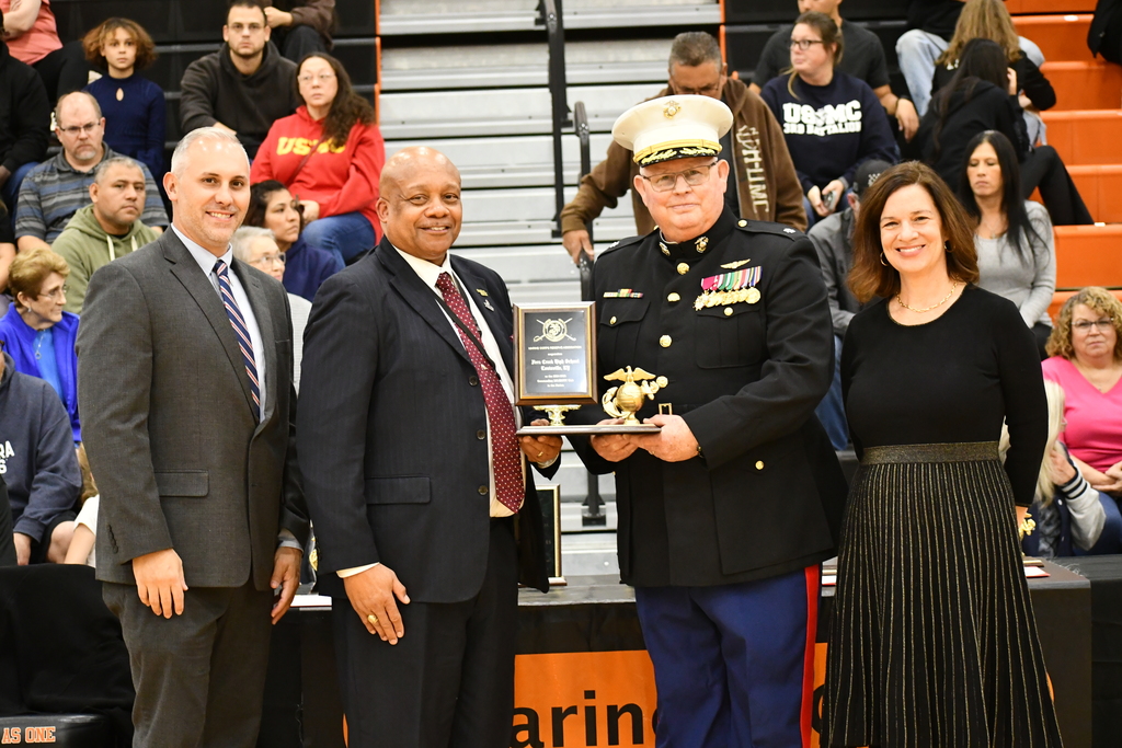 Four adults pose for a picture with an award.