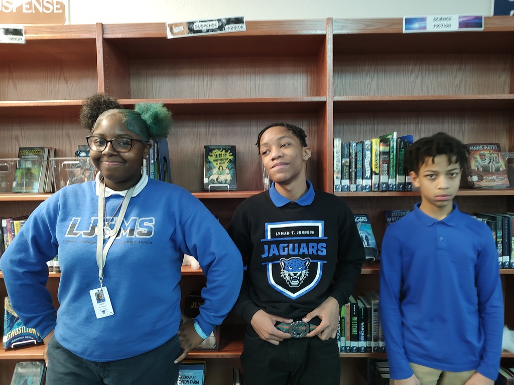 Spelling Bee Winners in 1st, 2nd, and 3rd place standing in front of bookshelves