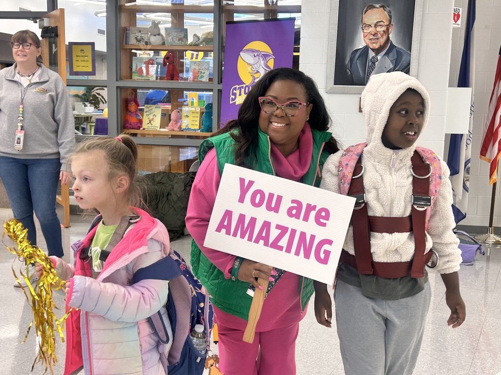 Mornings with Moms volunteers cheer for students as they enter the school building.