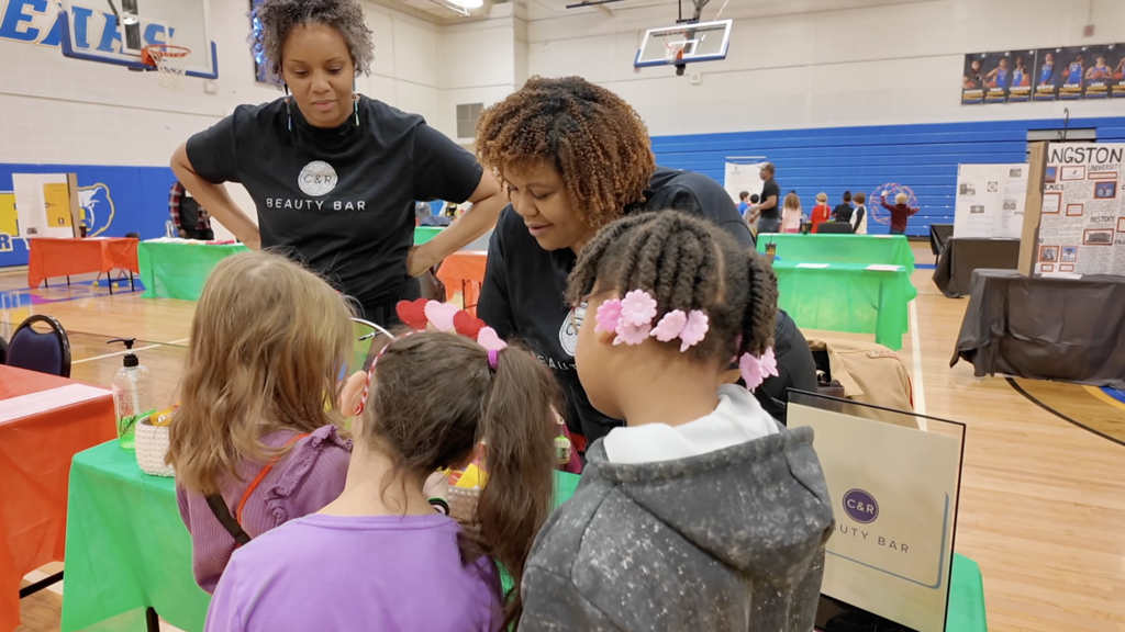 Two adults talk to three students during a career fair.