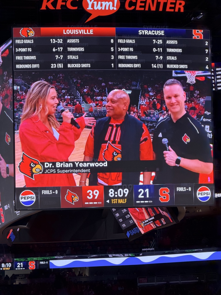 Dr. Yearwood talks to two adults at the UofL basketball game.