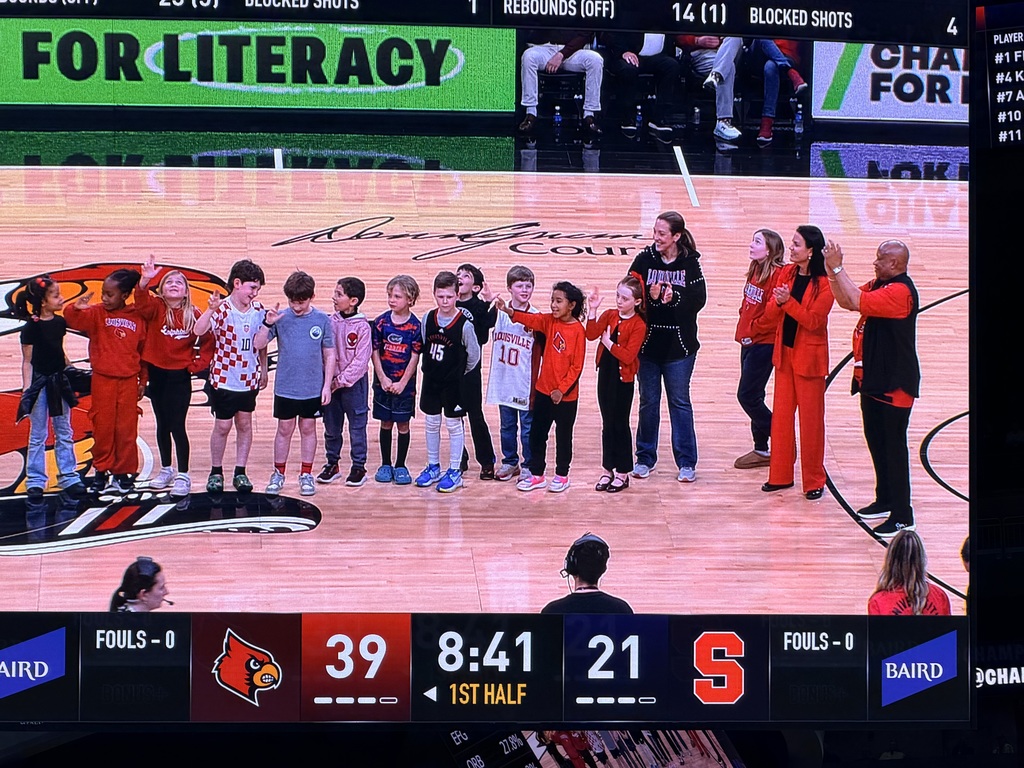 Students and adults stand on the court at the KFC Yum! Center.