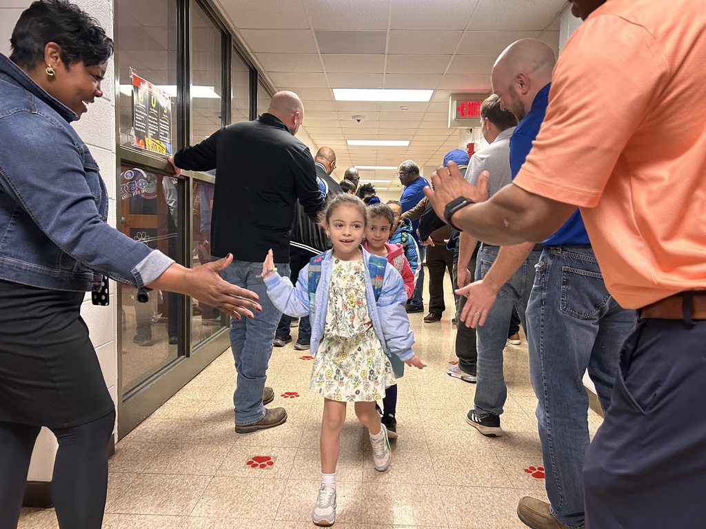 JCPS Flash Dad volunteers do high-fives and fist bumps with students as they walk down the hall.