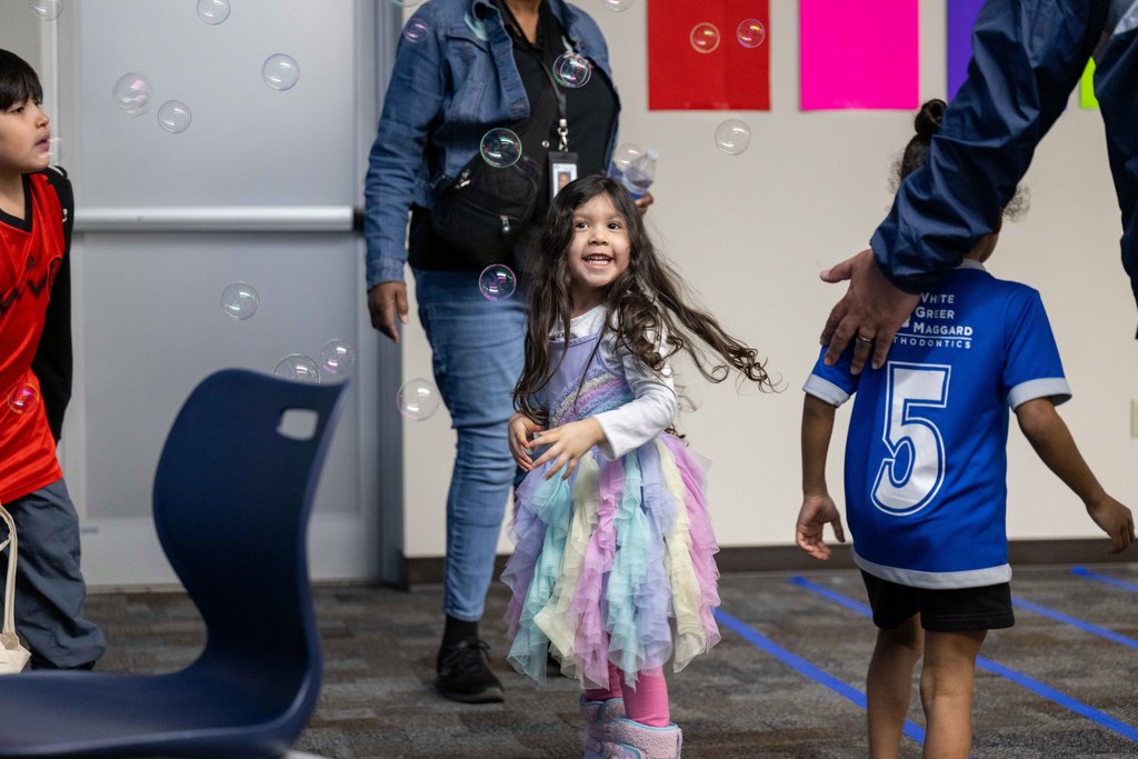 A child plays in bubbles and smiles.