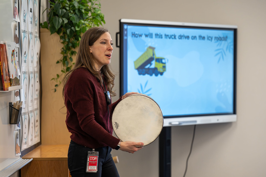 A teacher holds a drum.