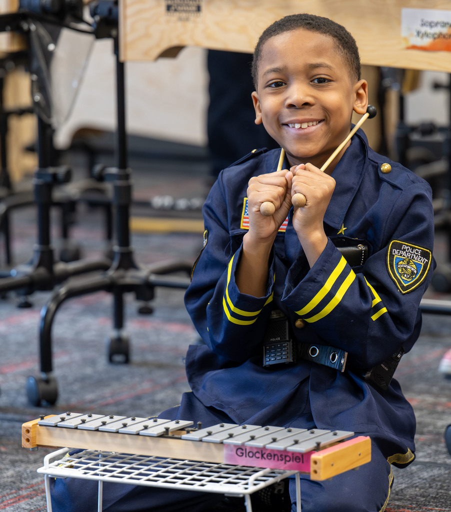A student sits behind a glockenspiel and smiles.