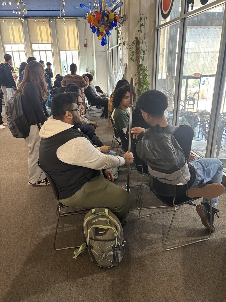 students sitting in chairs watching glass blowing demo