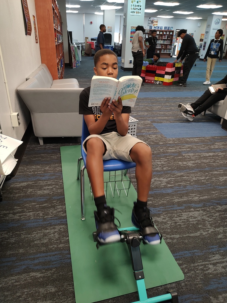 Student reading and using a bike pedal exerciser