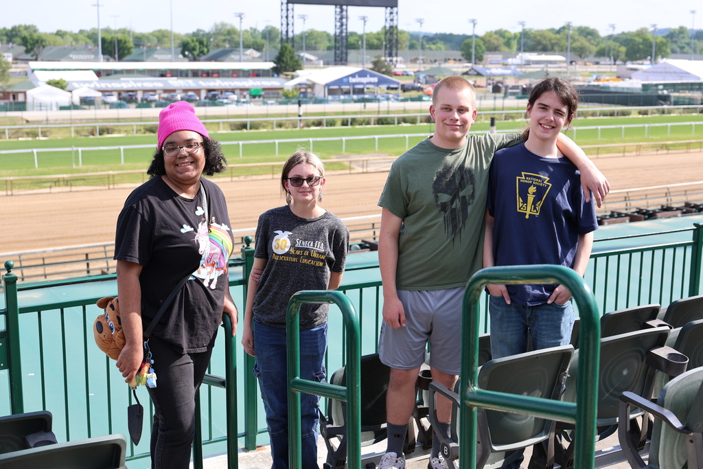 Four students pose for a picture in front of the Churchill Downs Racetrack. 