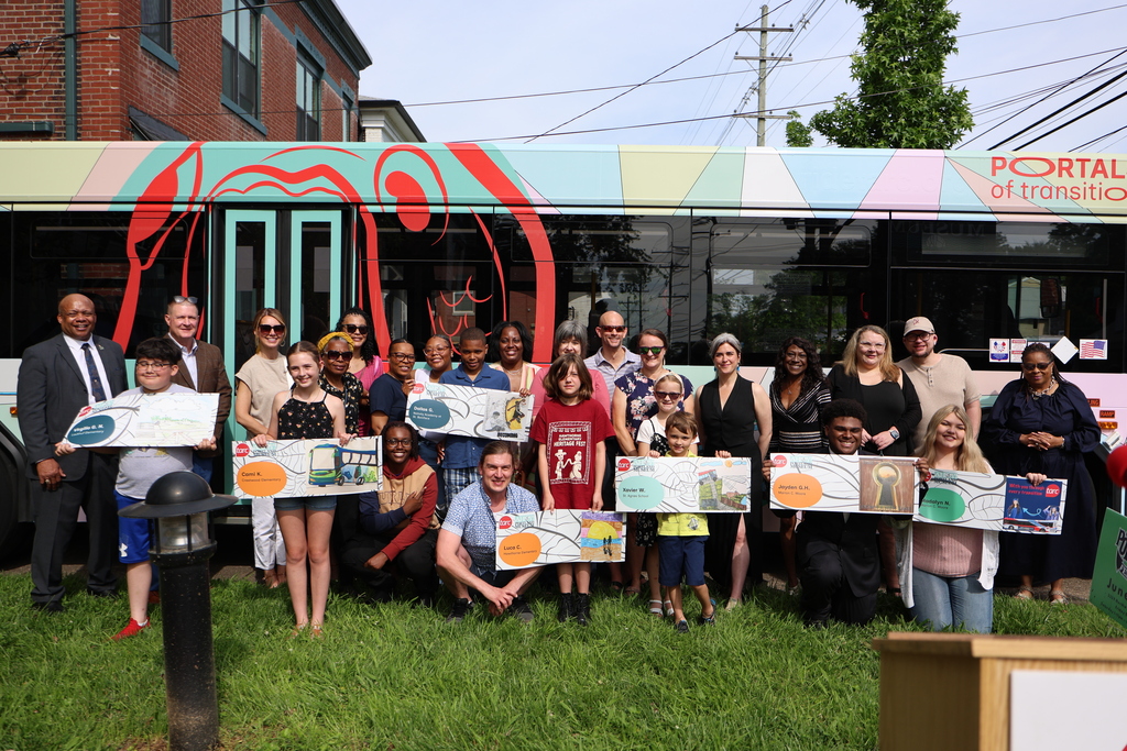 Students and adults pose for a photo in front of a TARC bus. 