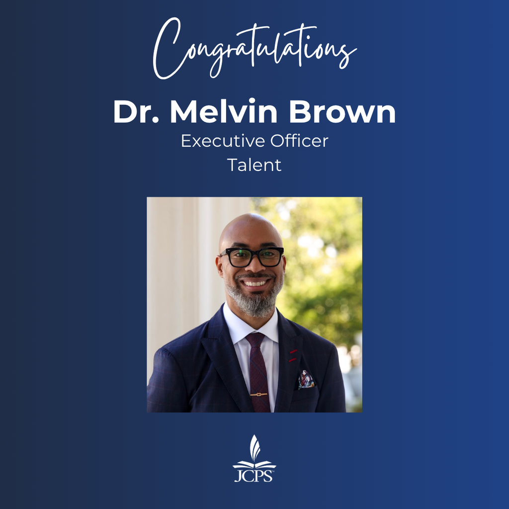 A graphic on a dark blue background that reads "Congratulations Dr. Melvin Brown, Executive Officer, Talent." Below the text is a square photograph of Dr. Brown, a smiling Black man with a shaved head, beard, and glasses, wearing a navy suit, white shirt, and tie. At the bottom center is the white logo for JCPS.