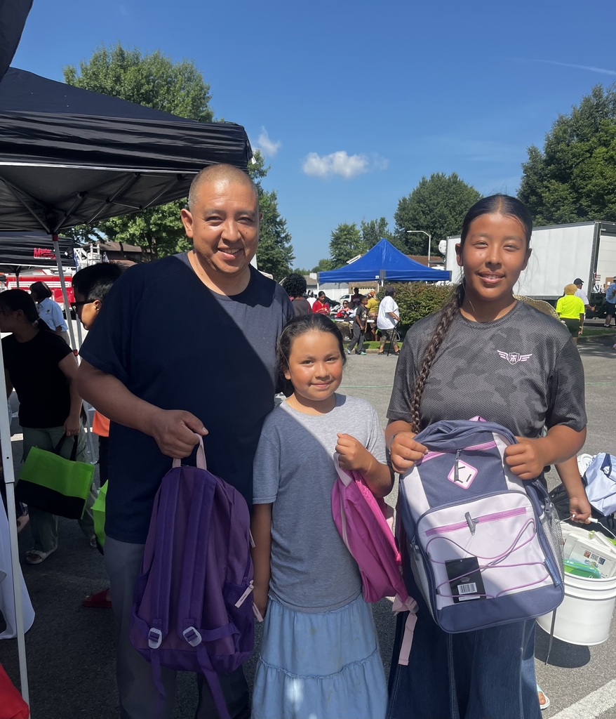 Two adults and a student hold backpacks and smile.