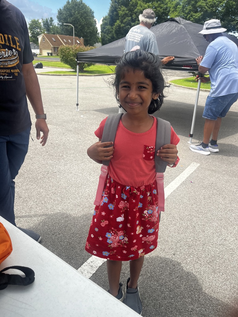 A student wears a backpack and smiles.
