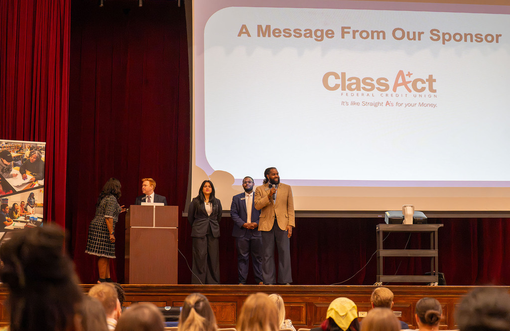 Class Act Federal Credit Union representatives stand on stage and talk to the crowd. 