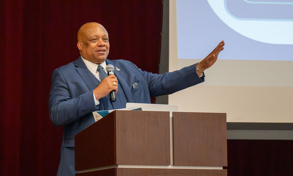 Superintendent Dr. Brian Yearwood stands at a podium and holds a microphone. 