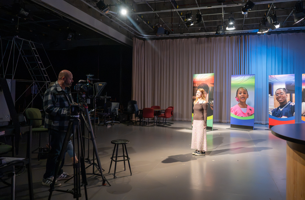 Two video coordinators work with a student to produce the "Our Kids" TV show.