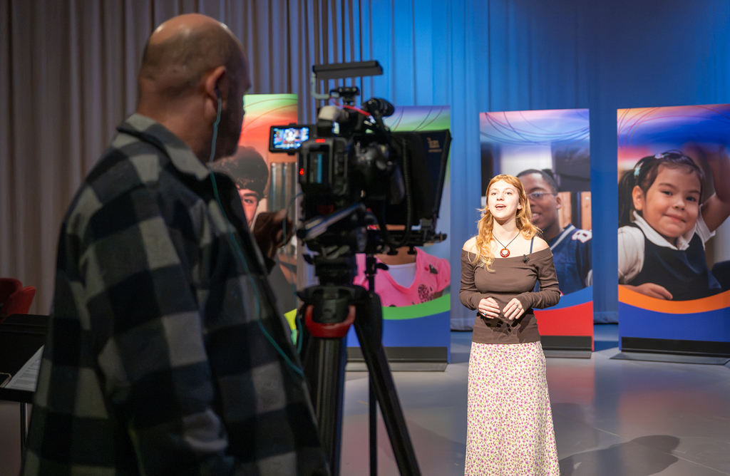 Two video coordinators work with a student to produce the "Our Kids" TV show.