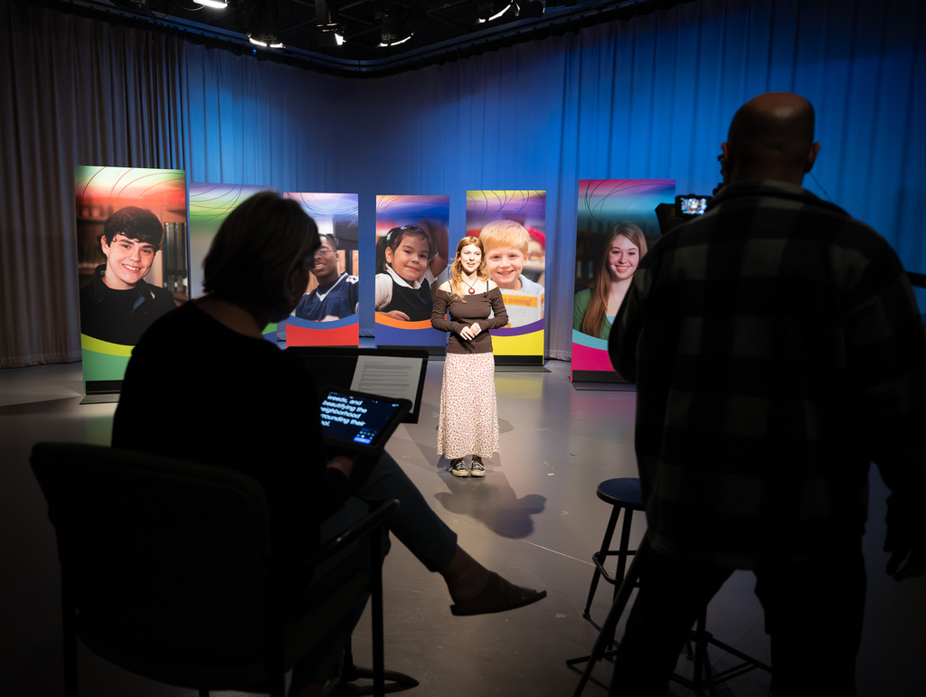 Two video coordinators work with a student to produce the "Our Kids" TV show.