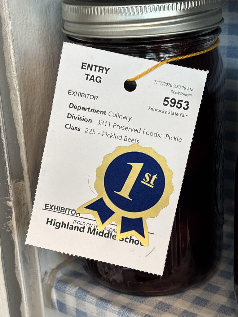 A first-place ribbon is attached to a jar of preserves.