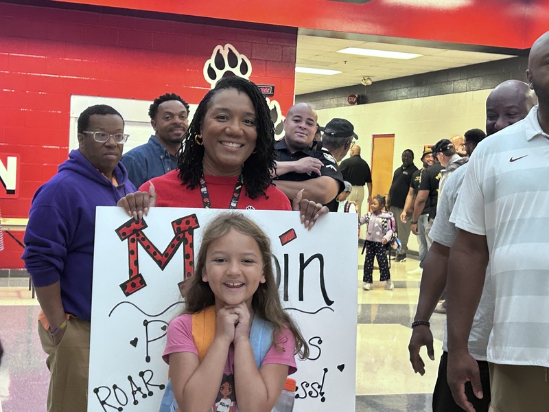 Smiling student infront of a sign that says "Maupin".