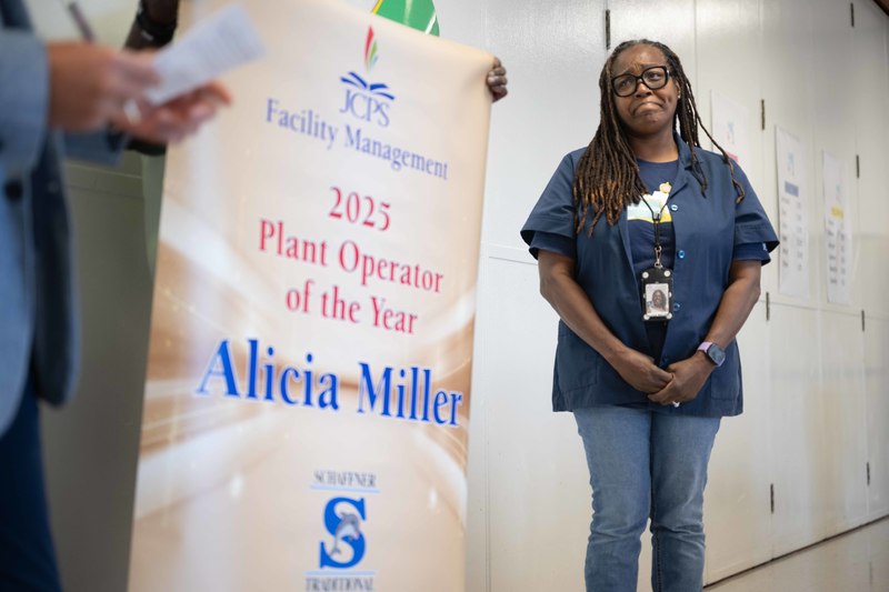 Alicia Miller stands beside a banner bearing her name