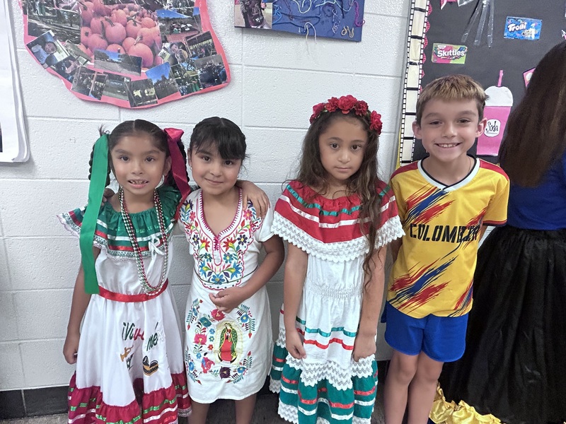 Four students wearing traditional clothing, and a soccer uniform, smiling for a photo.