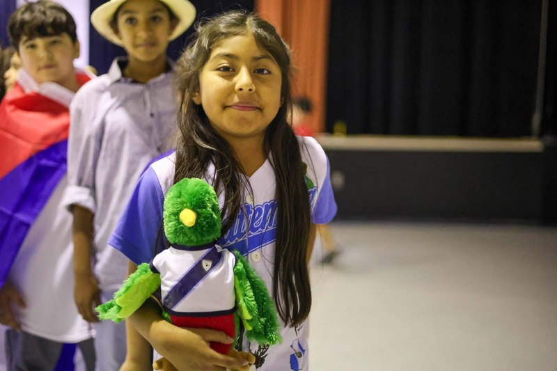 Student dressed in a jersey, holding a stuffed animal