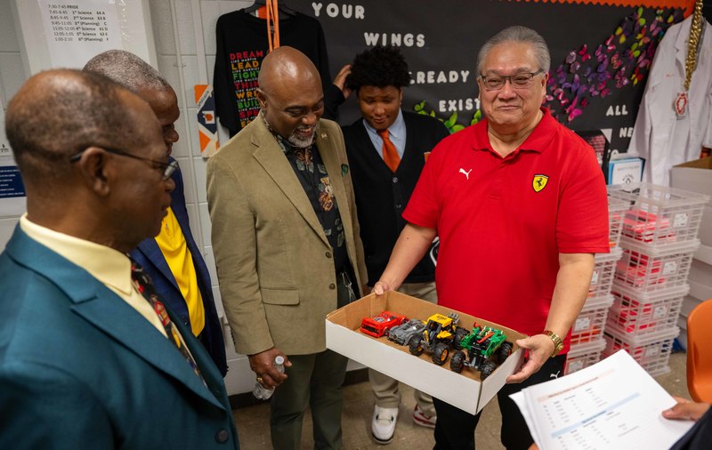 A teacher holding lego projects for the group to see.
