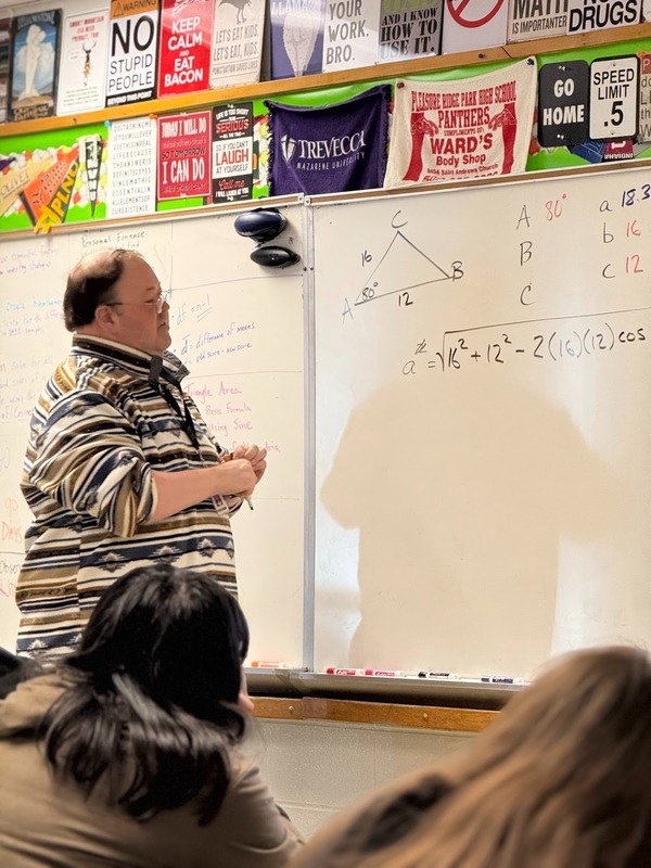 A teacher stands at the front of the class.