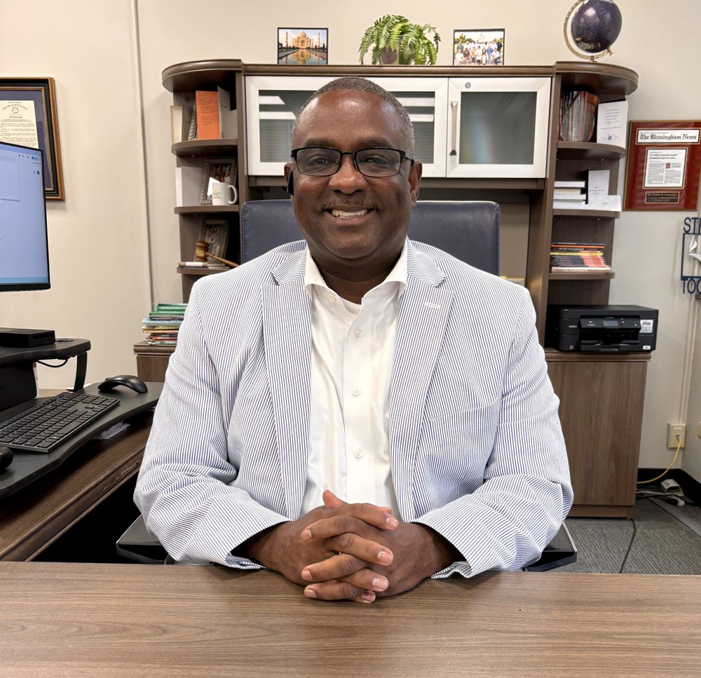 Superintendent Dr. Walter Gonsoulin sits at a desk and smiles