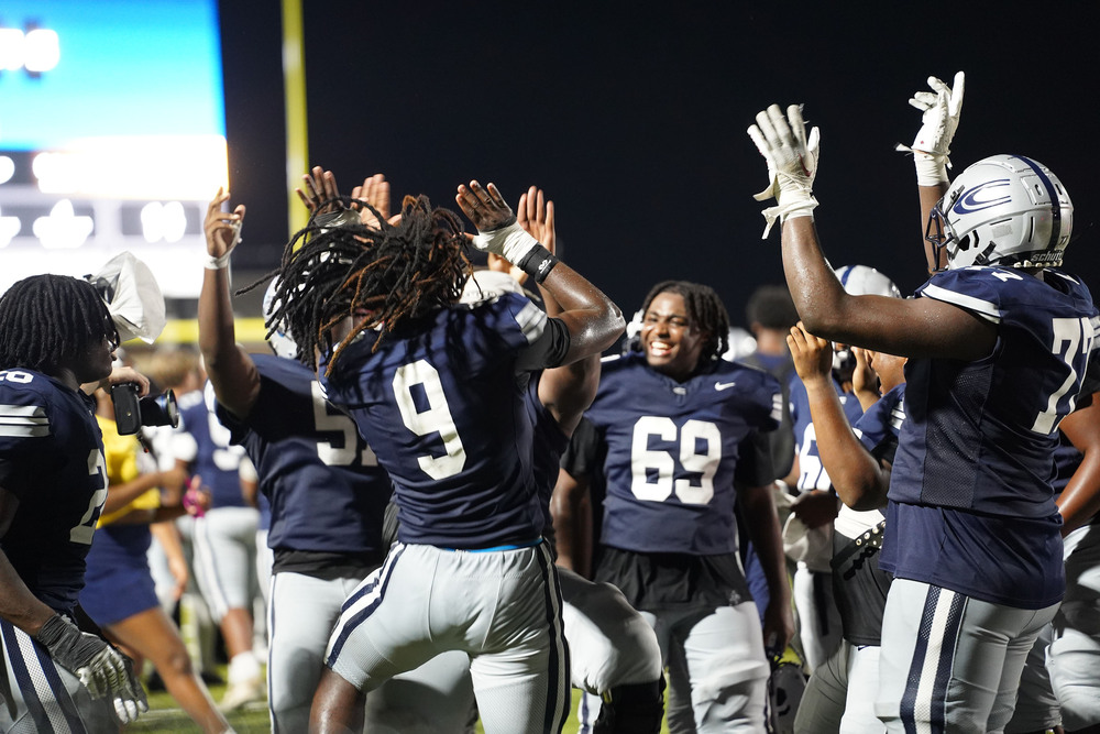Clay-Chalkville High School football players jump up and down, celebrating their win.