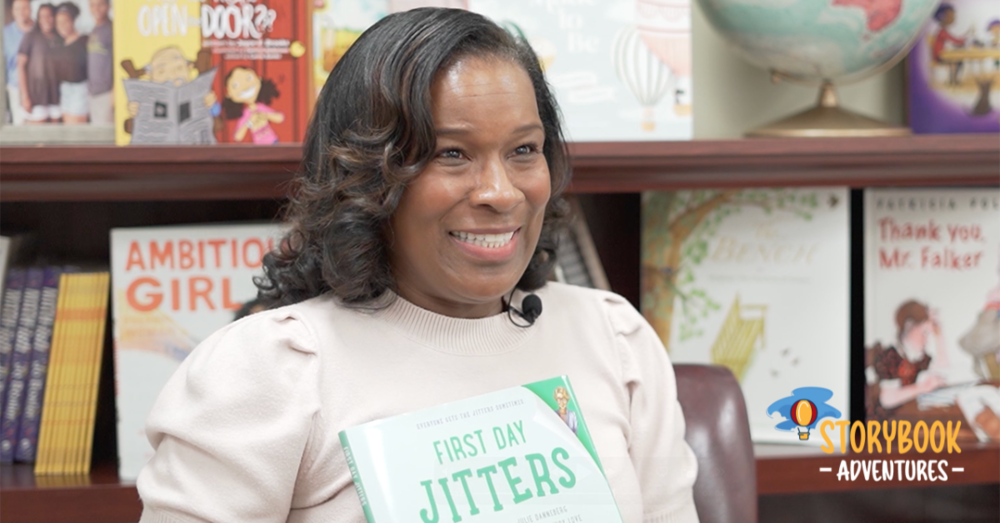 Dr. Watkins holds up the book "First Day Jitters" and sits in front of a book shelf.
