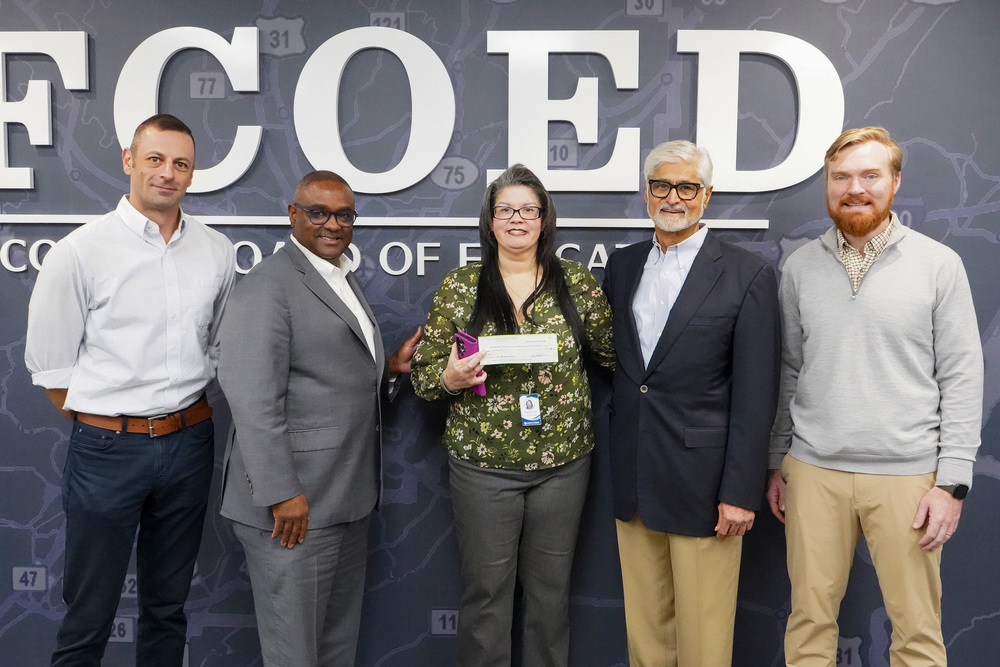Members of Bhate Geosciences stand with Superintendent Dr. Walter Gonsoulin and Director of the Education Foundation, Dr. Gertrudis Hunter. Dr. Hunter is holding up a check presented to the Foundation by Bhate for $10,000.