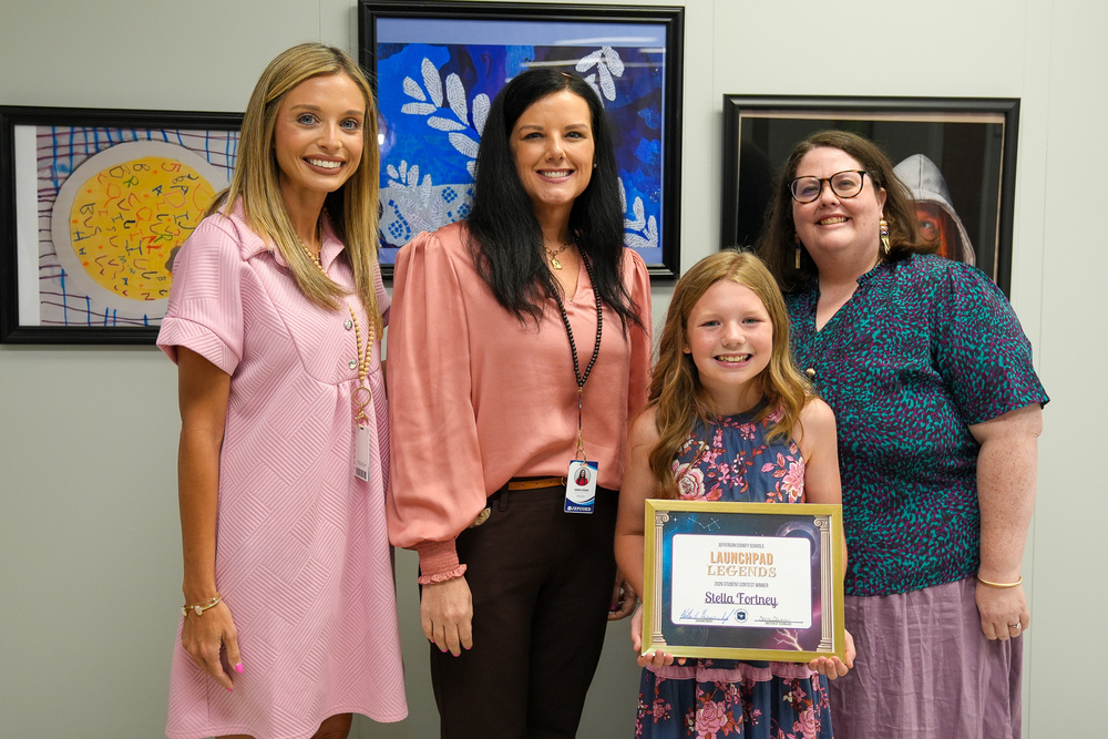 Bagley student Stella Fortney, Bagley Principal Shalina Hammock, JEFCOED Technology Director Sara Fenn, and JEFCOED Assistant Director of Technology, Charlsie Wigley stand together and pose for a photo. Stella holds an award in her hands.