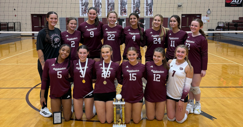 Gardendale High School JV volleyball players stand together for a team photo inside a school gym.